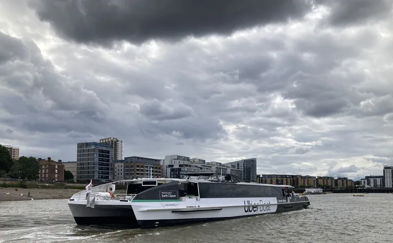 A low catamaran river bus crossing the Thames at Greenwich under a cloudy sky