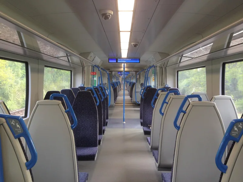 Empty blue seats down the length of a walk-through Thameslink Class 700 carriage
