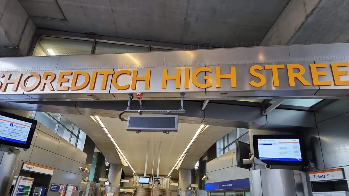 Large orange letters spelling SHOREDITCH HIGH STREET across the concrete entrance of the Overground station