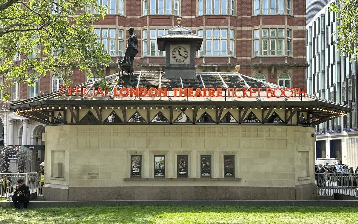 The Official London Theatre ticket booth in Leicester Square, its red sign lit above the entrance