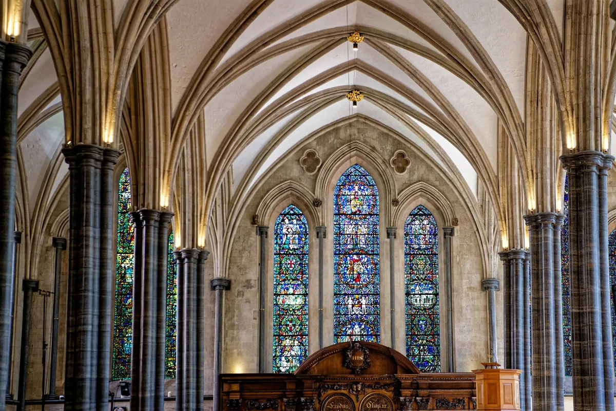 Tall lancet windows of stained glass and dark polished columns in the chancel of Temple Church in the City of London