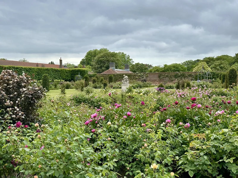 The walled rose garden at Hampton Court Palace, with mown lawn, low hedges and a stone statue