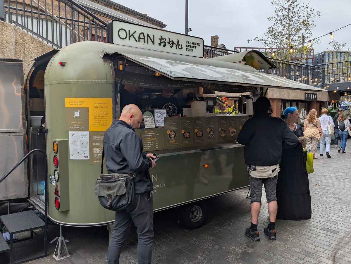 Customers queueing at a Japanese street food trailer at an outdoor market in London