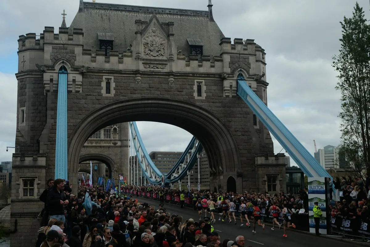 Runners streaming across Tower Bridge between crowds of spectators during the London Marathon