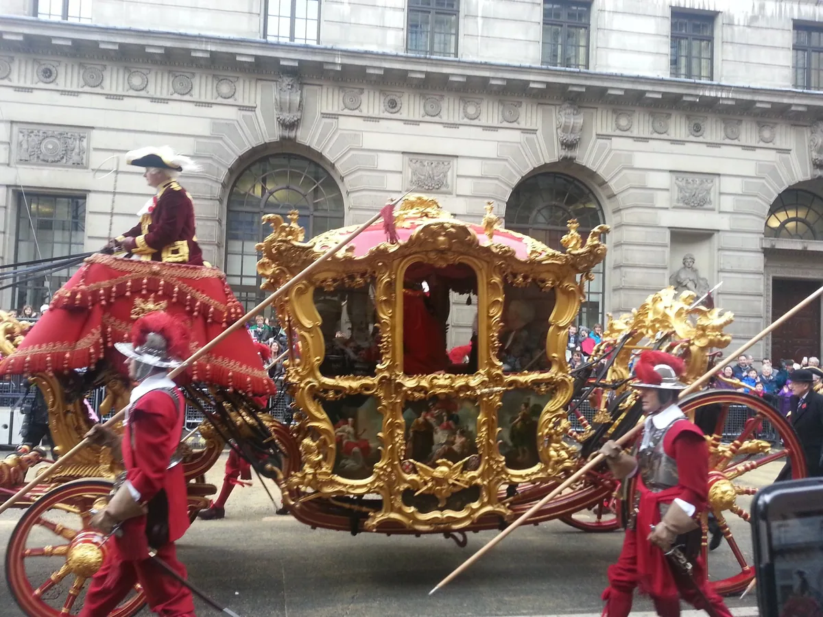 The gilded Lord Mayor's State Coach passing City offices, escorted by pikemen in red uniforms