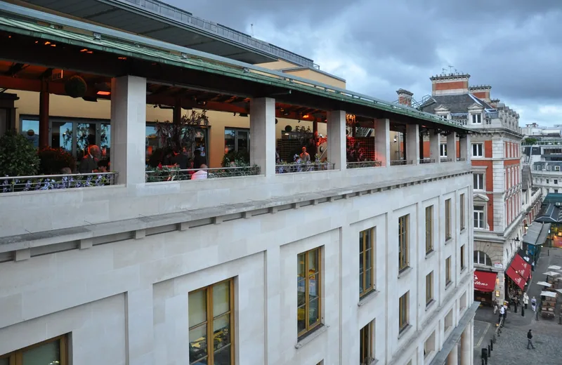 The Royal Opera House terrace overlooking Covent Garden, with people behind the windows during an interval