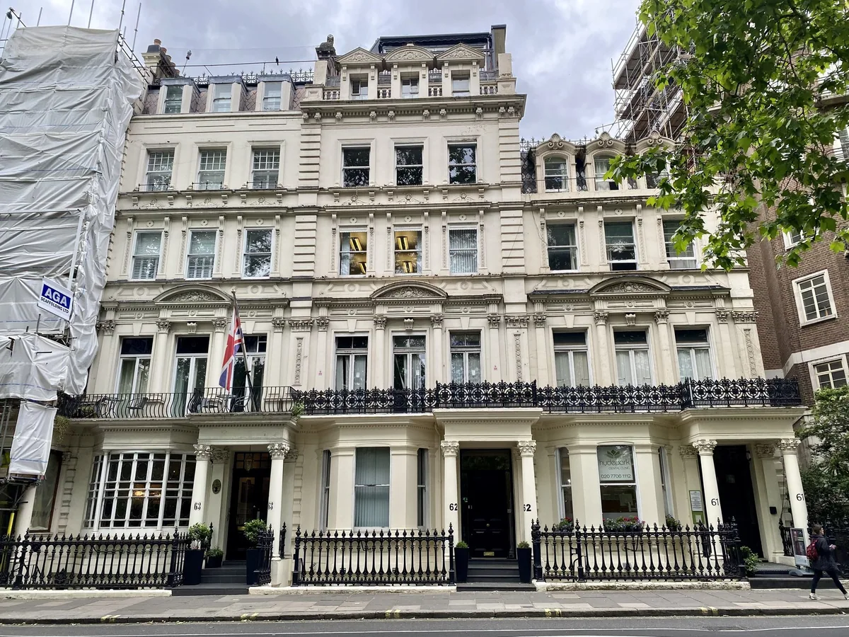 A white stucco Victorian terrace on Bayswater Road with iron railings and canopied front entrances