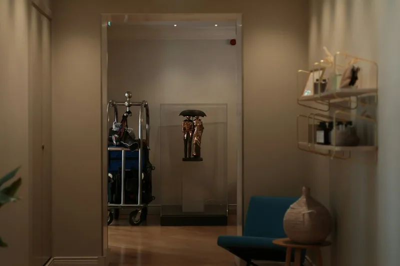 A loaded bellhop luggage trolley parked in a side room off a hotel lobby
