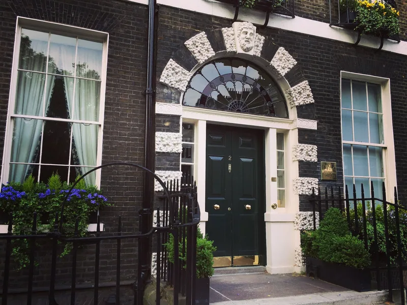 A black front door with a rusticated stone arch and fanlight on a Bedford Square house