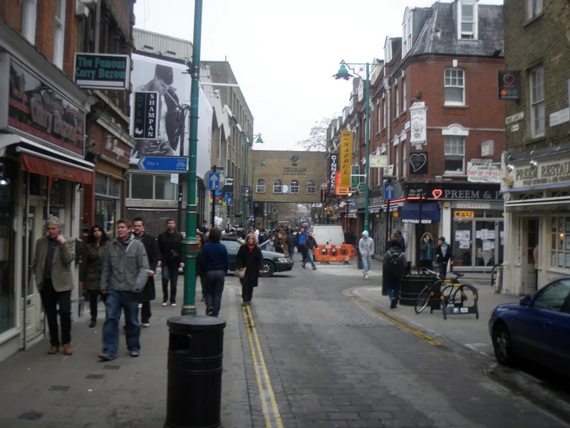 People walking past the shops and restaurants that line Brick Lane in east London