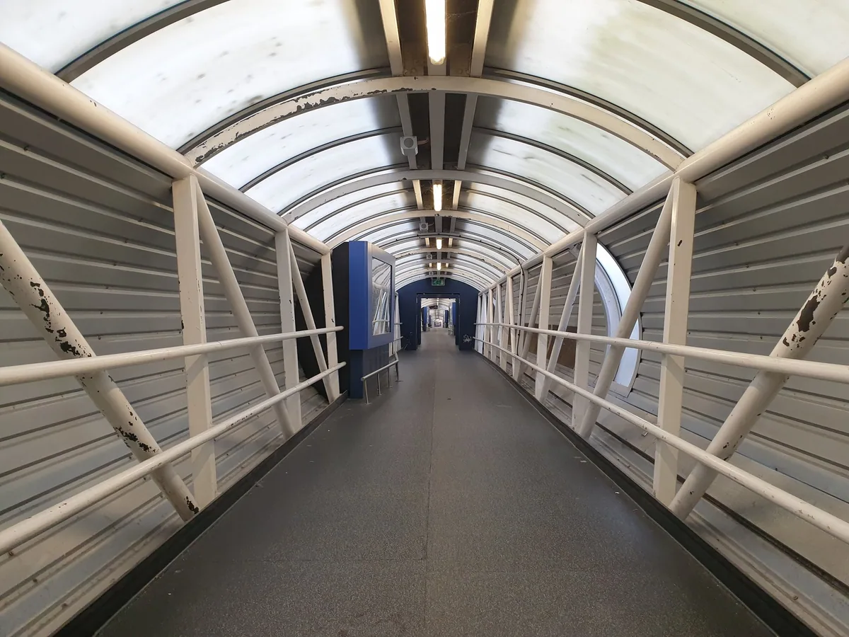 An empty covered walkway leading from a Heathrow terminal to the airport hotels