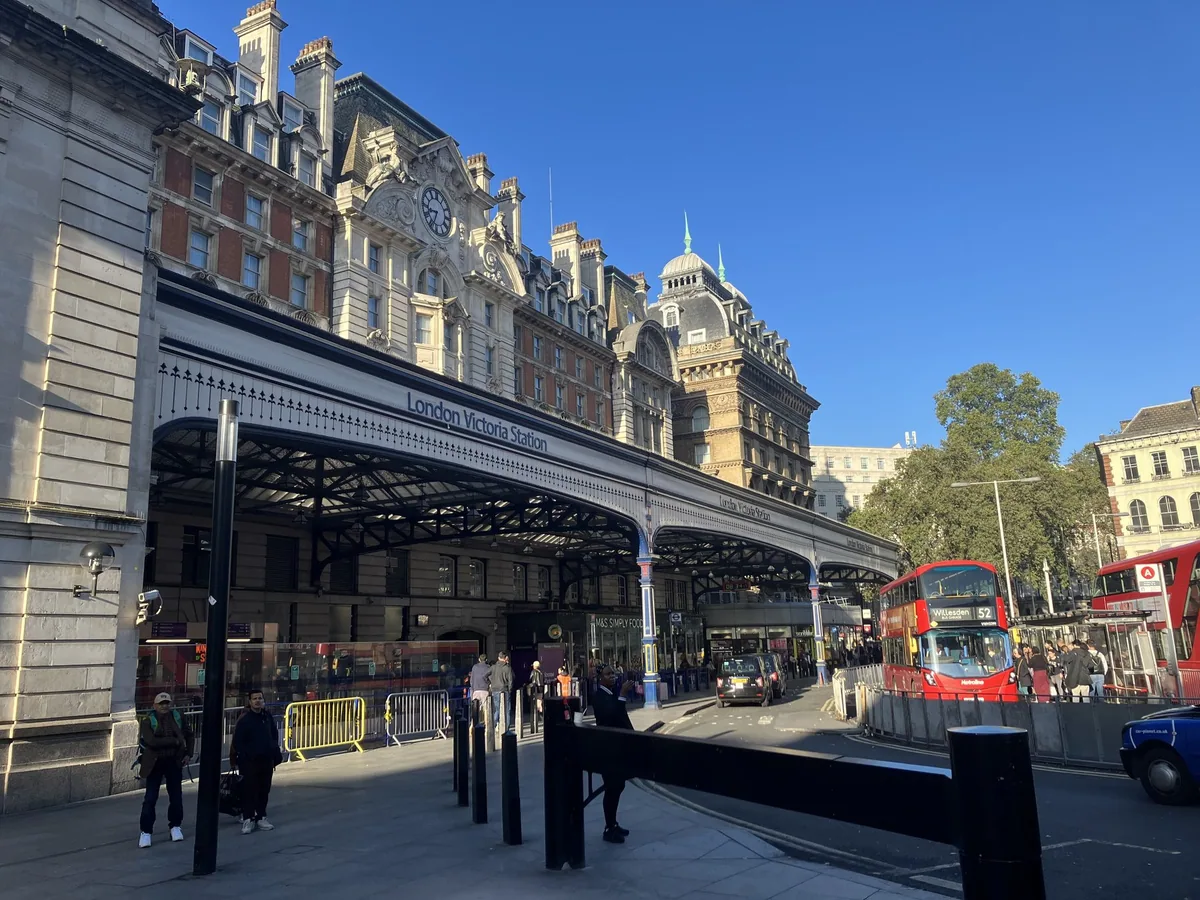 The glazed entrance canopy of London Victoria station with red buses waiting outside