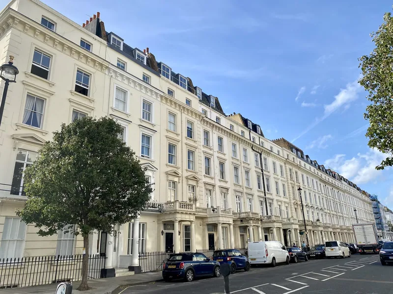 A long terrace of white stucco houses on Belgrave Road in Pimlico under a blue sky