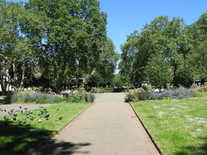 A gravel path between lawns and flowerbeds in a leafy Bloomsbury garden square